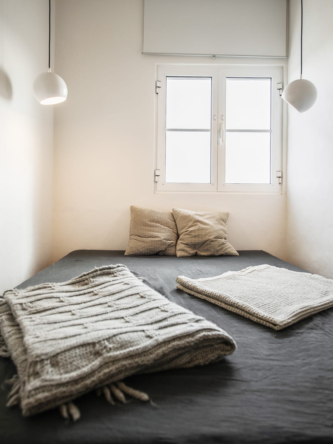 Minimalistisches Zimmer mit Bett, zwei Kissen und zwei Decken
