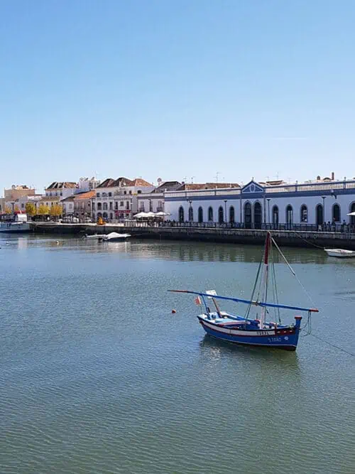 Boot auf dem Wasser schippert vor einer portugiesischen Stadt umher