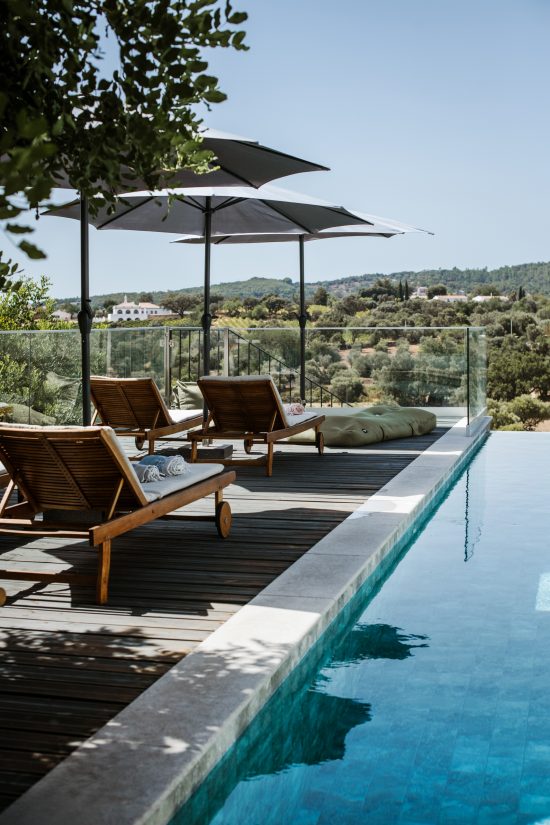 Heated infinity pool with wooden deck at CASA KALU, surrounded by the picturesque Algarve landscape