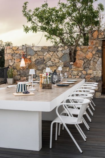 Mesa de jantar exterior convidativa na CASA KALU com parede de pedra rústica e um toque mediterrânico no Algarve